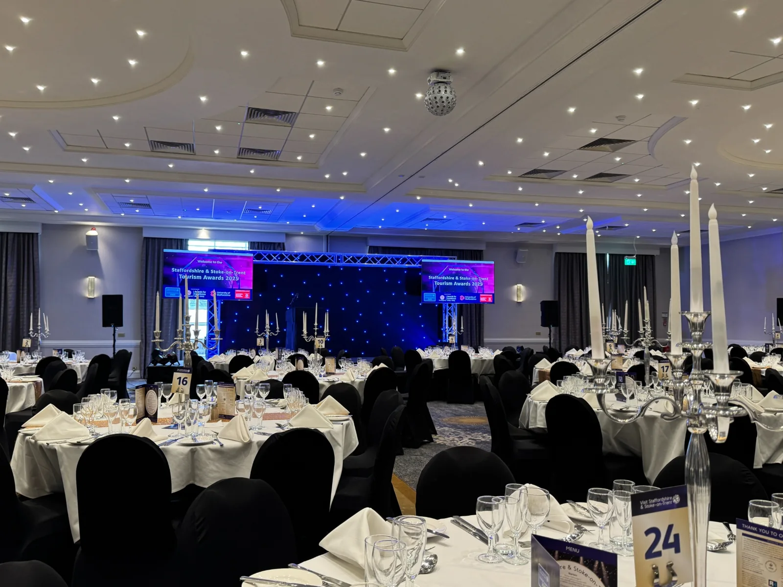 Awards venue prepared with tables, stage, lighting and large screens