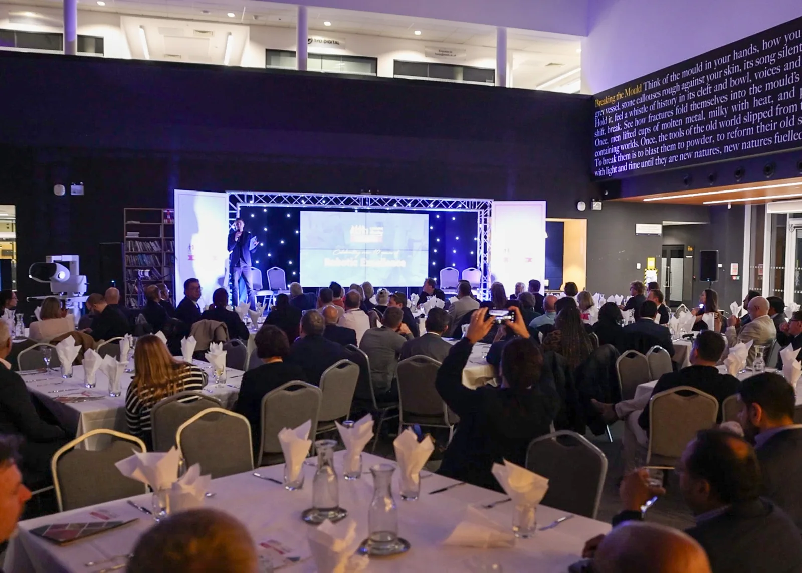 Guests watching a live presentation with stage lighting and screens